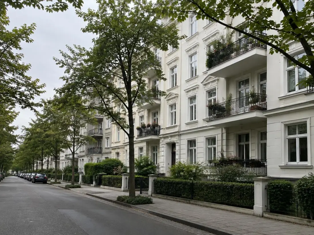 Tree-lined residential street with light-coloured period apartment buildings in a German city